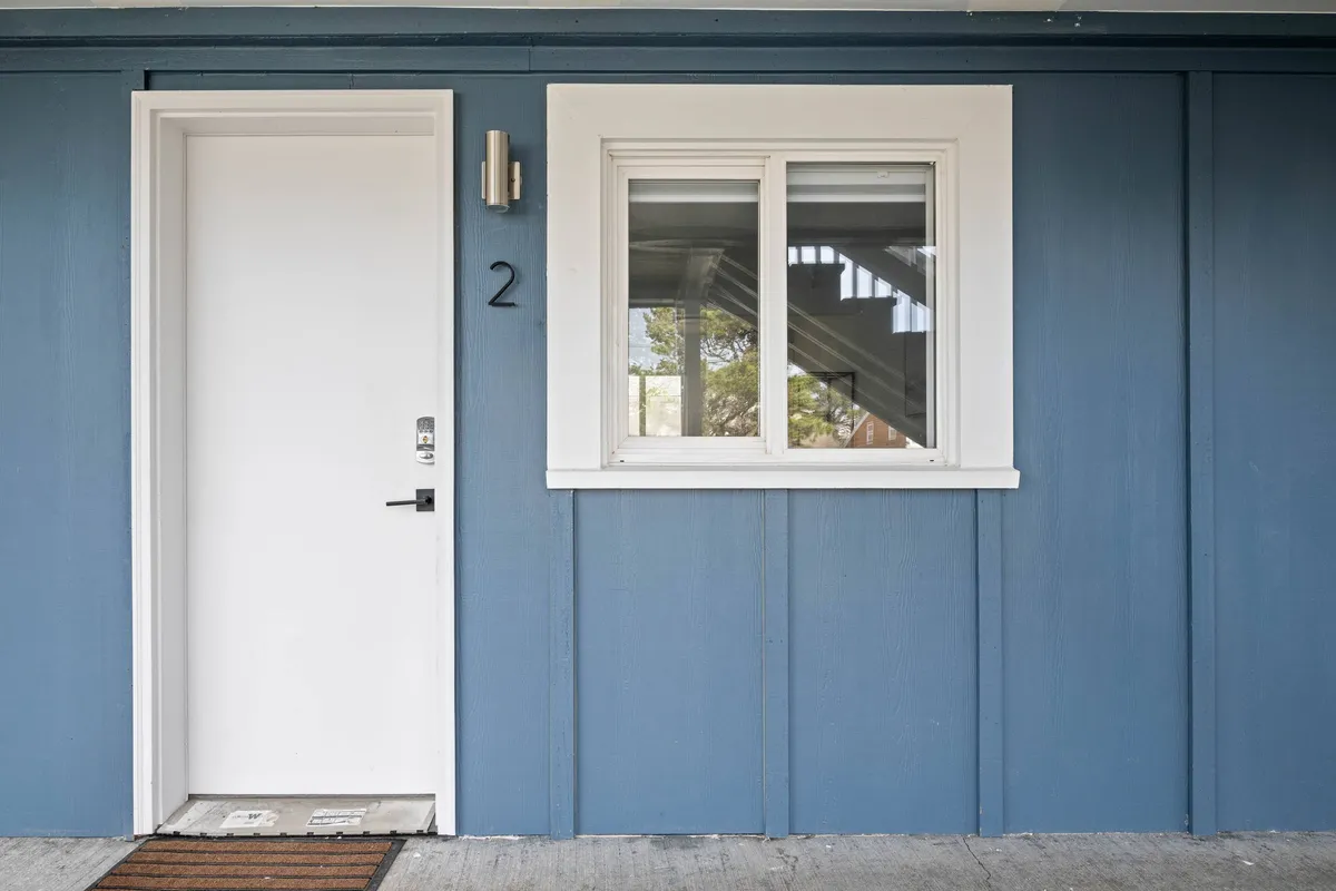 This image captures the exterior of the property, focusing on the welcoming front door, a sunlit window, and the clearly visible house number. The scene evokes the anticipation of stepping out or returning from nearby adventures, and hints at a friendly neighborhood atmosphere.